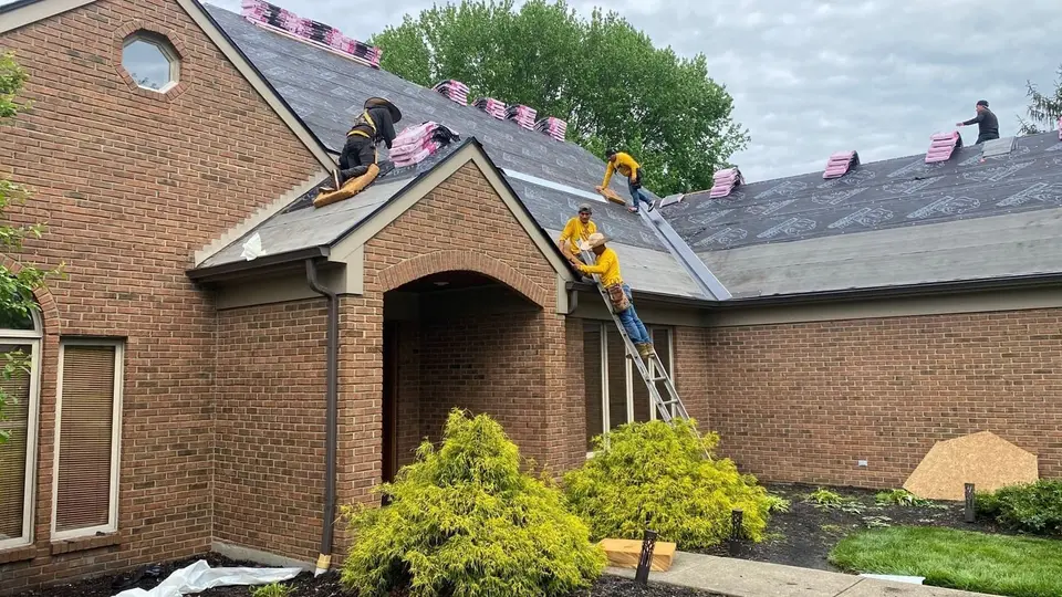 Crew members installing underlayment and shingles on a brick home
