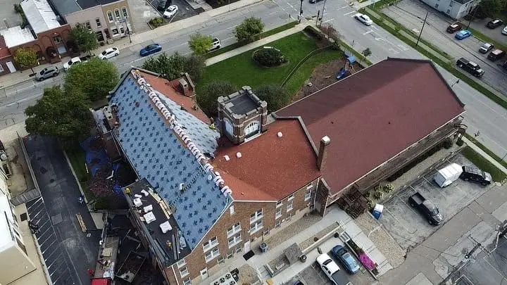 Aerial view of a church roof replacement in progress with new underlayment on one slope