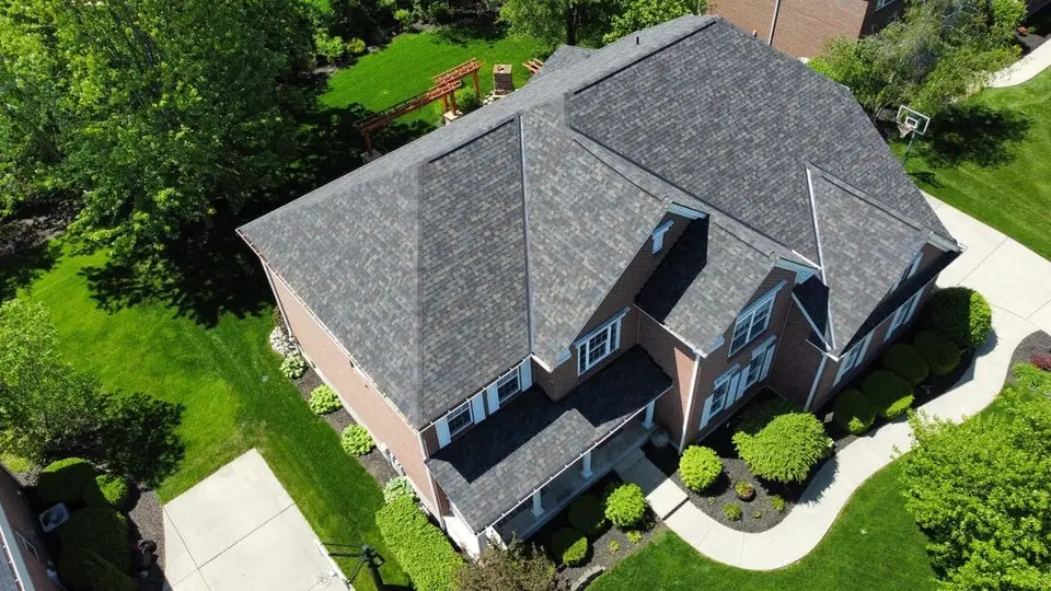 Aerial view of a finished gray hip roof on a two-story brick home