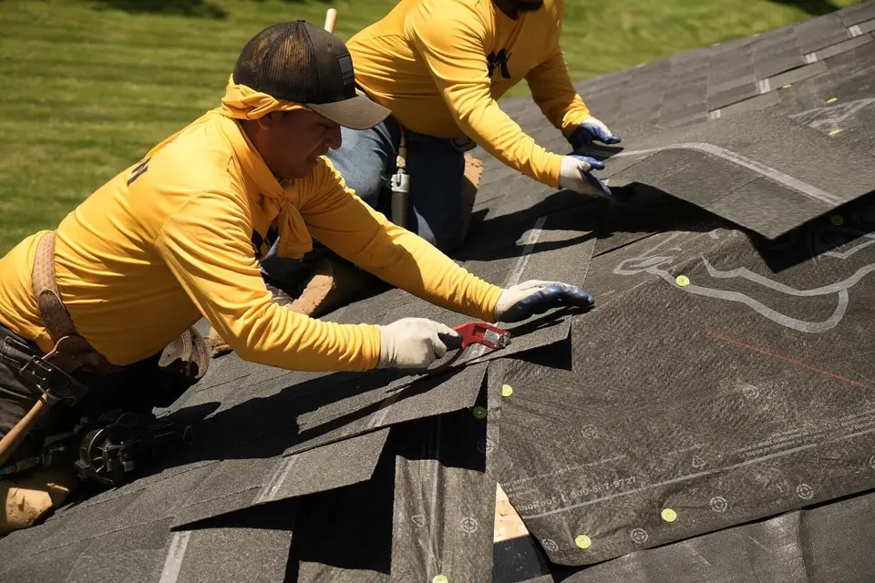 Two Rooftop Relief crew members cutting and setting architectural shingles