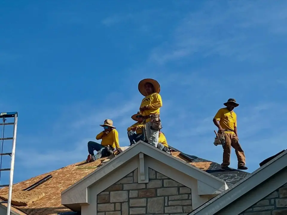Rooftop Relief crew working along the peak of a roof under a clear blue sky