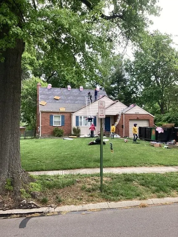Crew working on the roof of a brick Cape Cod style home during a replacement